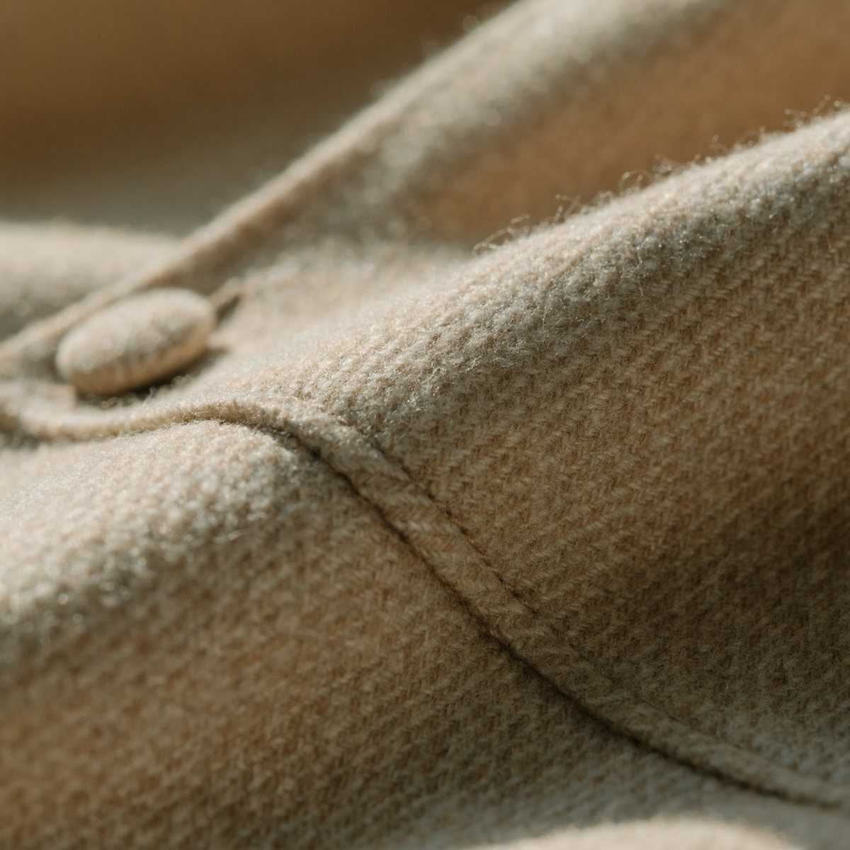Close detail of a finely woven camel wool twill and a covered button